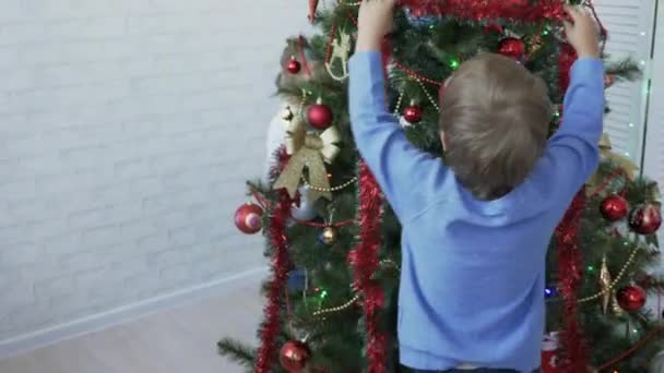 Kinder schmücken tagsüber Weihnachtsbaum im hellen Raum — Stockvideo