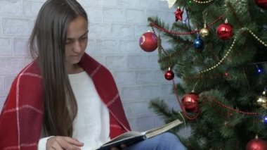 Noel ağacı yakınındaki güzel kadın okuma kitabı