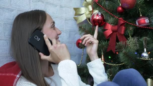 젊은 여성이 휴대 전화로 말하기와 크리스마스 트리 근처 미소. — 비디오