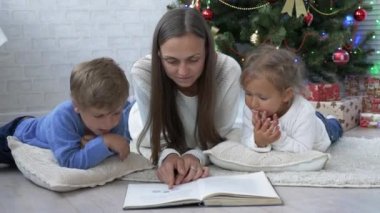 Genç diğer gönüllülük a kitap Noel ağacı yakınındaki katta iki çocuklu anne