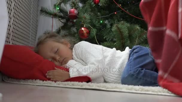 Cute little girl sleeping under Christmas tree at morning — Stock Video