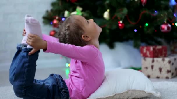 Schattig klein meisje doen yoga oefening op de verdieping, naast de kerstboom — Stockvideo