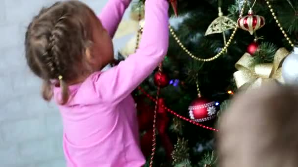 Due bambini piccoli fratello e sorella che decorano l'albero di Natale di giorno — Video Stock