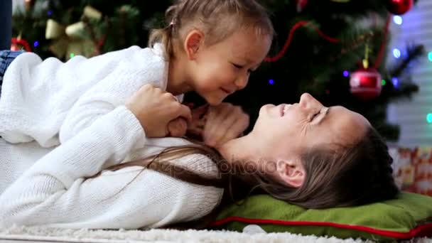 Счастливая мать веселится со своей дочерью в рождественское время возле рождественской елки — стоковое видео