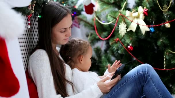 Genç anne ve kızı bir Noel dekore edilmiş iç smartphone kullanarak — Stok video