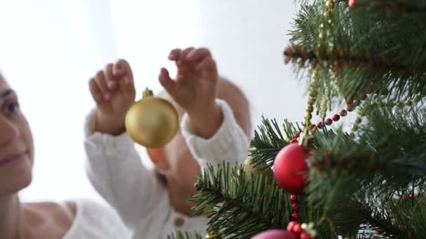 Chicas felices, madre e hija decorando un árbol de Navidad en casa . — Vídeo de stock