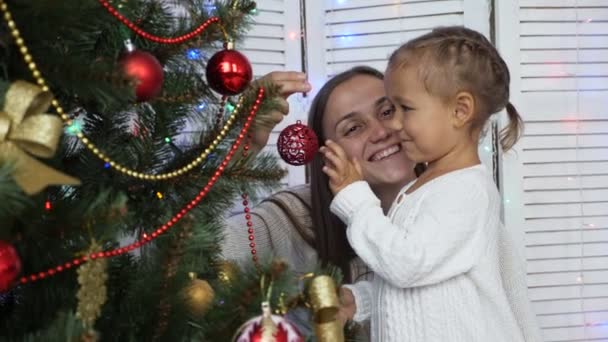 Glückliche Mädchen, Mutter und Tochter schmücken zu Hause einen Weihnachtsbaum. — Stockvideo