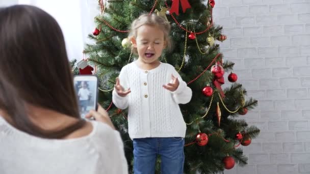 Alegre niña bailando y jugando al mono cerca del árbol de Navidad — Vídeo de stock