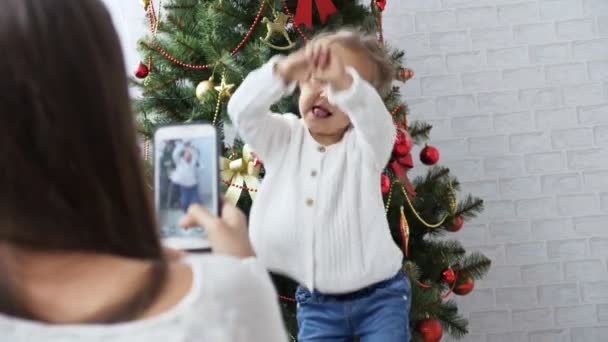 Χαρούμενα κοριτσάκι χορεύοντας και παίζοντας το ape κοντά στο χριστουγεννιάτικο δέντρο — Αρχείο Βίντεο