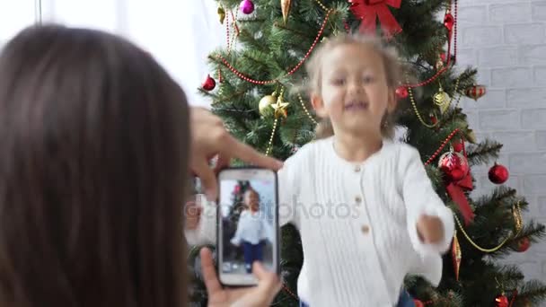 fröhliches kleines Mädchen tanzt und spielt den Affen neben dem Weihnachtsbaum