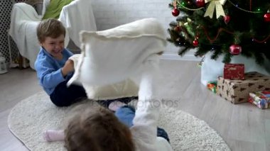Oynak kardeşler Noel ağacının yanındaki evde yastık ile mücadele.