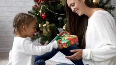 Çocuk veren Noel hediyesi annesi ile Noel ağacı arka planı için