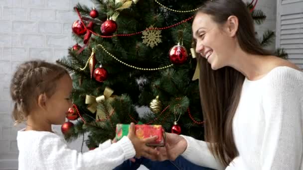 Mãe dando presente de Natal para seu filho com árvore de Natal no fundo — Vídeo de Stock