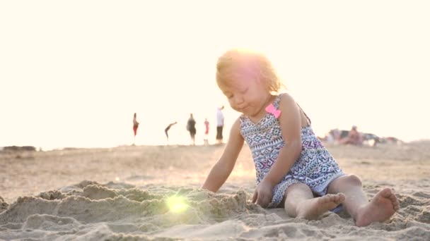 Schattig meisje gebouw zand Kasteeltje op het strand. — Stockvideo