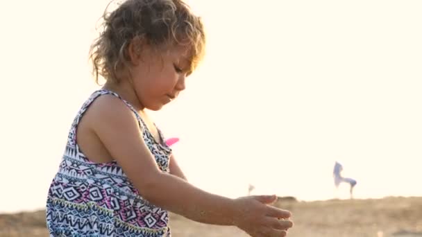 Schattig meisje gebouw zand Kasteeltje op het strand. — Stockvideo