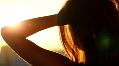 Genç kadın saç balkonda günbatımında dokunmadan arka görmek