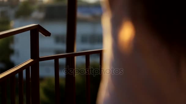 Joven mujer yendo en el balcón viendo la puesta del sol, tiro medio — Vídeos de Stock