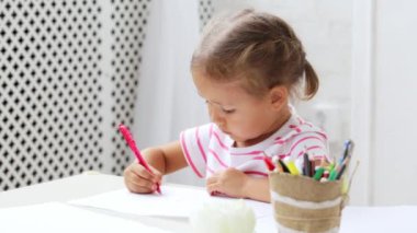 Bir şey çizim duruldu beyaz masa başına oturmuş sevimli okul öncesi kız.