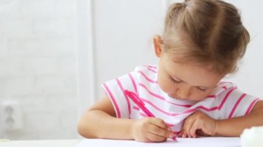 Bir şey çizim duruldu beyaz masa başına oturmuş sevimli okul öncesi kız.