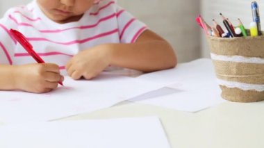 Bir şey çizim duruldu beyaz masa başına oturmuş sevimli okul öncesi kız.