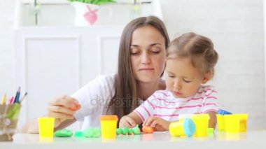 Genç çekici anne küçük şirin kızı ile oynamak kil modelleme ile