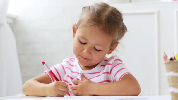 Schattig preschool meisje zit door de witte tabel gericht op tekening iets. — Stockvideo