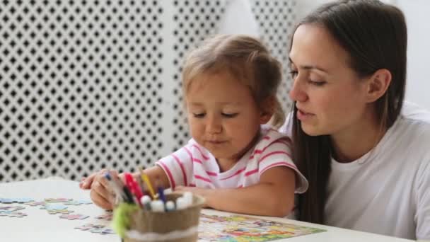 Мать и дочь вместе решают головоломку в светлой гостиной — стоковое видео