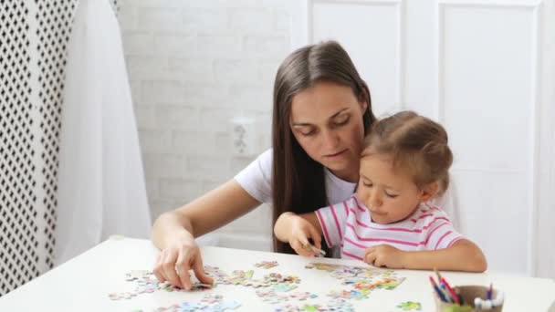 Matka a dcera dělá puzzle dohromady ve světle obývacím pokoji