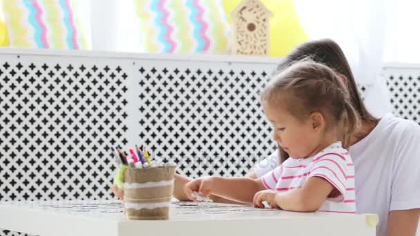 Mother and daughter doing a puzzle together in the light living room — Stock Video