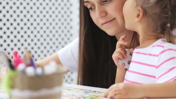 Mother and daughter doing a puzzle together in the light living room — Stock Video