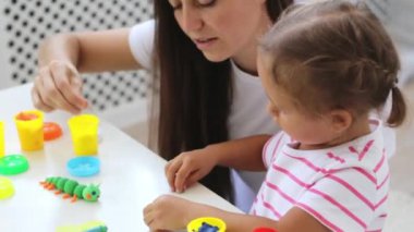 Genç çekici anne küçük şirin kızı ile oynamak kil modelleme ile