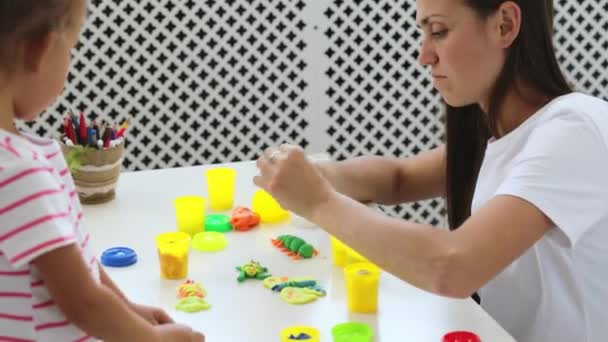 Young attractive mother with little cute daughter play with modeling clay — Stock Video