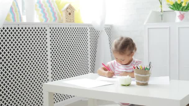 Schattig preschool meisje zit door de witte tabel gericht op tekening iets. — Stockvideo