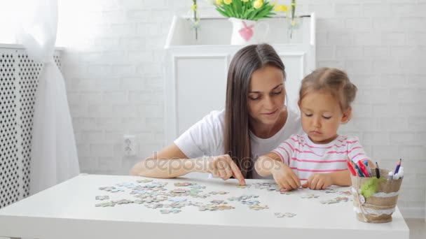 Mor och dotter gör ett pussel tillsammans i det ljusa vardagsrummet — Stockvideo