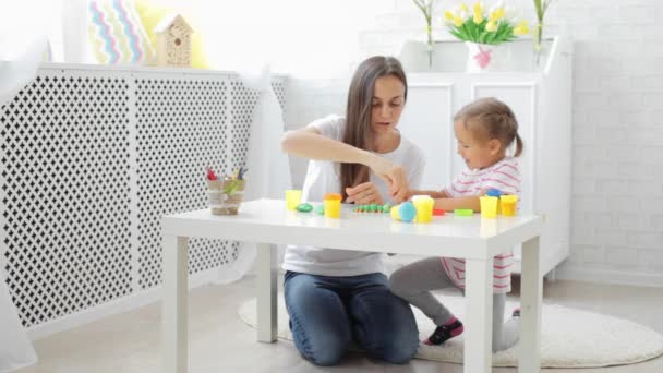 Mutter mit süßer kleiner Tochter spielt mit Modelliermasse im hellen Wohnzimmer. — Stockvideo