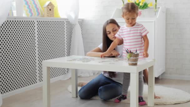 Mãe e filha fazendo um quebra-cabeça juntos na sala de estar luz — Vídeo de Stock