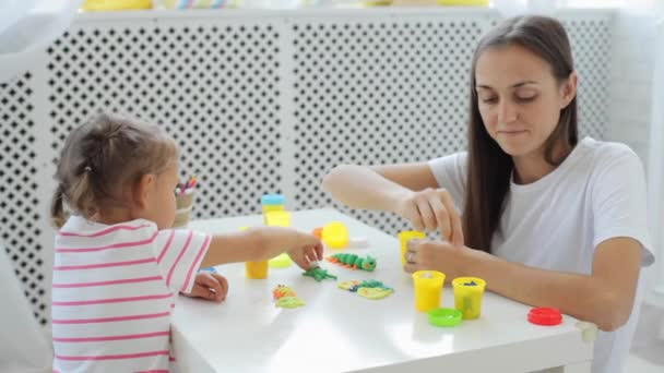 Мати з милою маленькою донькою грає з моделюванням глини у світлій вітальні . — стокове відео