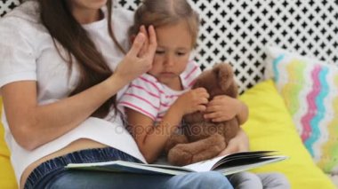 Genç anne küçük kızı için kitap okumak.