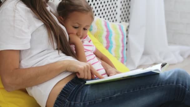 Genç anne küçük kızı için kitap okumak. — Stok video