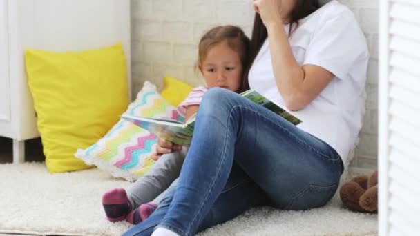 Jovem mãe leitura livro para sua filhinha . — Vídeo de Stock