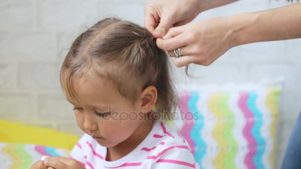 Молода жінка робить прищіпки на волоссі дочки — стокове відео