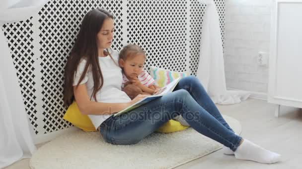 Junge Mutter liest Buch für ihre kleine Tochter. — Stockvideo