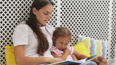 Genç anne küçük kızı için kitap okumak.