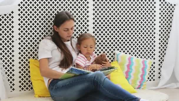 Joven madre leyendo libro para su pequeña hija . — Vídeos de Stock