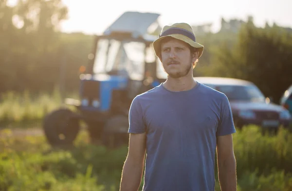 Agricultor no campo com o trator em segundo plano na fazenda orgânica — Fotografia de Stock