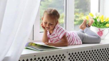 Pencere evde kitap okurken küçük şirin kız portresi kapatın.