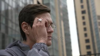 Mühendis üniformalı arka planda bina ile gözlük kaldırır.