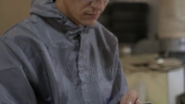 Genç yetişkin adam işçi fabrikada akıllı telefon kullanarak bir gözlük closeup görünümü