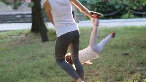 Jovem mãe com sua filhinha se divertindo e brincando no parque — Vídeo de Stock