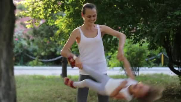 Junge Mutter mit ihrer kleinen Tochter hat Spaß und spielt im Park — Stockvideo